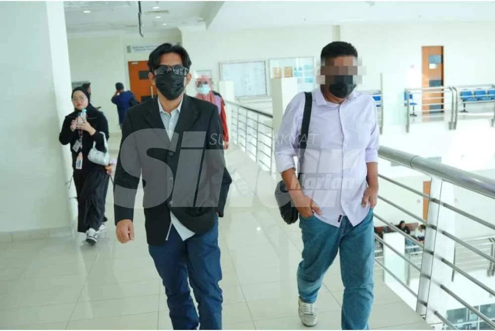 Idi Johan (kiri) memakai kemeja berwarna hitam hadir ke Mahkamah Sesyen Klang pada Isnin.