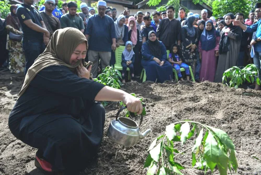 Seorang ahli keluarga tidak dapat menahan kesedihan ketika menyiram air mawar di di pusara lima sekeluarga yang maut dalam kemalangan mebabitkan kenderaan utiliti sukan (SUV) dengan sebuah lori di Pinang Tunggal, Foto Bernama