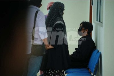 Idi Johan (duduk) memakai kemeja berwarna hitam hadir ke Mahkamah Sesyen Klang pada Isnin.