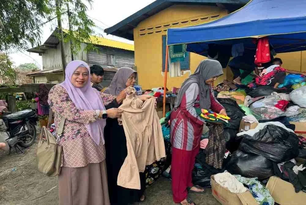 Mangsa kebakaran mengambil baju yang sesuai untuk mereka.
FOTO ADILA SHARINNI WAHID