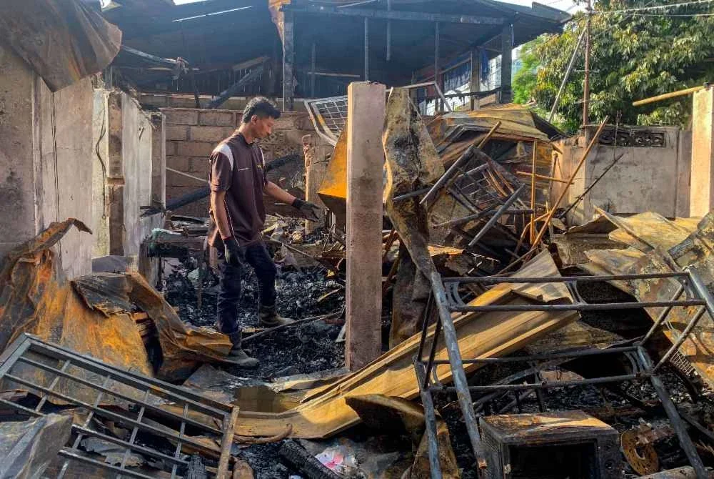 Mangsa kebakaran, Mohd Khairul Azwan Annuar, 34, mencari sisa-sisa barangan yang masih boleh digunakan selepas kediamannya musnah dalam kebakaran membabitkan 27 rumah di Kampung Gok Gapur. Foto Bernama