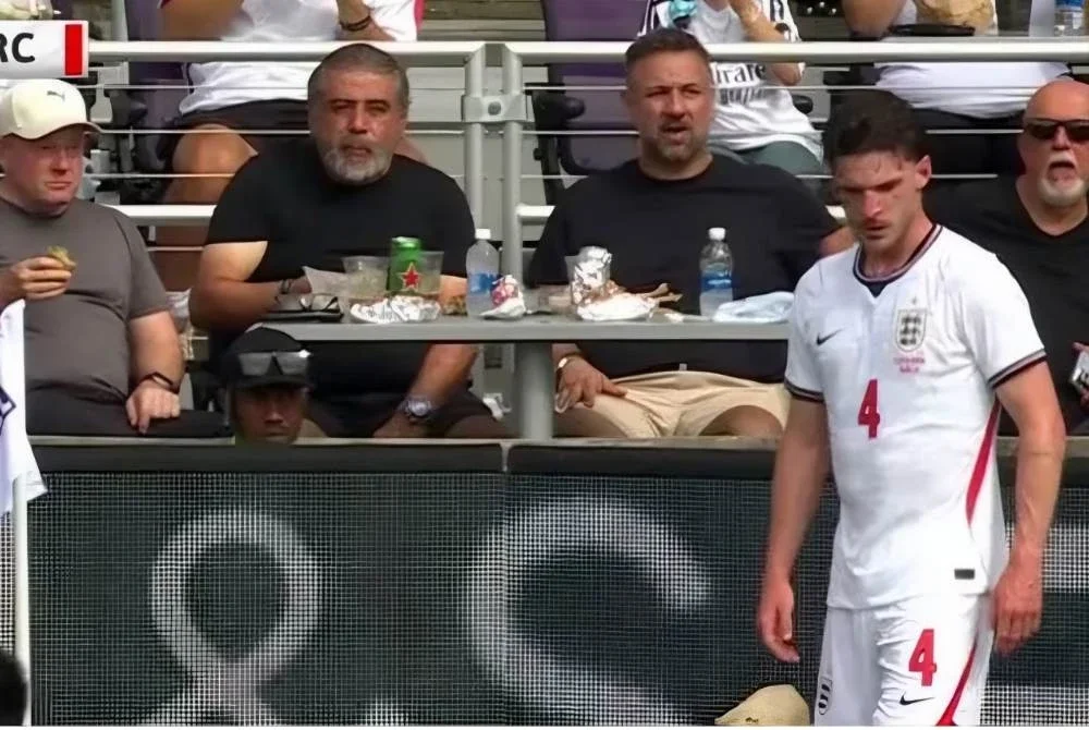 Peminat dilihat menikmati burger di meja makan tepi padang ketika pemain tengah England, Declan Rice bersedia mengambil sepakan sudut. - Foto: Agensi