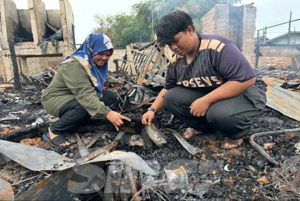 Muhammad Arif Haikal (kanan) dan Siti Salmiah (kiri) melihat sisa buku yang hangus dalam kebakaran di Gok Kapur. FOTO ADILA SHARINNI WAHID