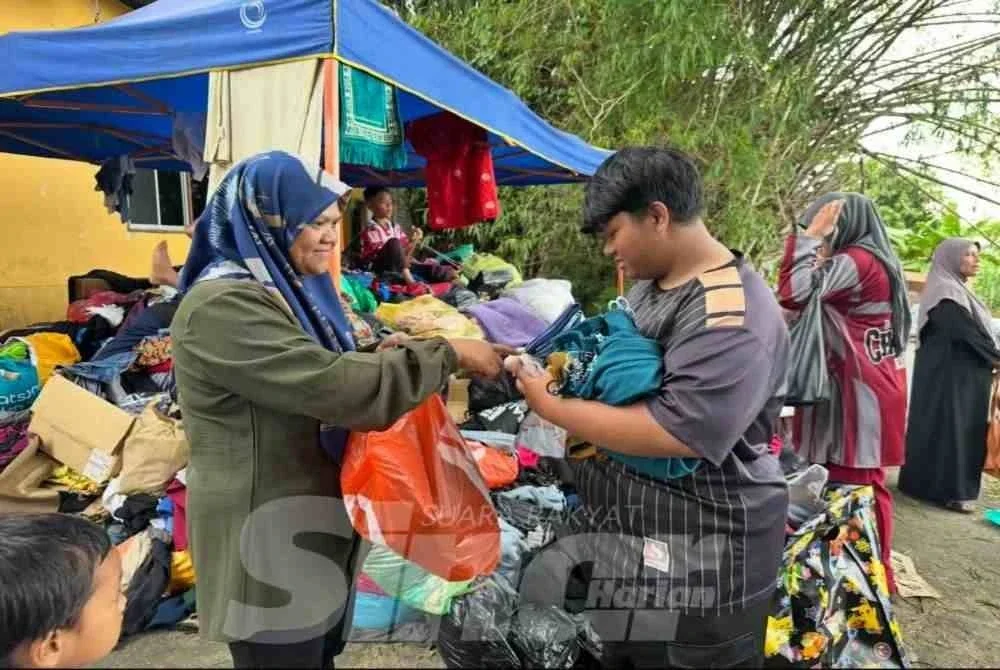 Muhammad Arif Haikal (kanan) yang membantu Siti Salmiah (kiri) memilih baju yang disedekah orang ramai.
FOTO ADILA SHARINNI WAHID