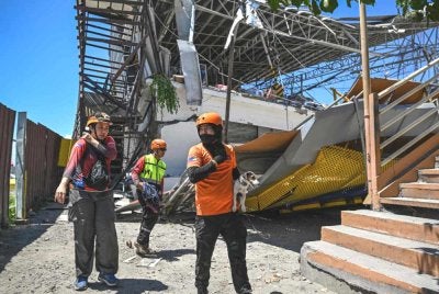 Anggota penyelamat bersama seekor anjing pengesan menjalankan operasi mencari dan menyelamat di lokasi sebuah bangunan yang runtuh susulan gempa bumi berukuran 7.8 magnitud di General Santos City, Filipina, pada 9 Jun 2026. Foto AFP