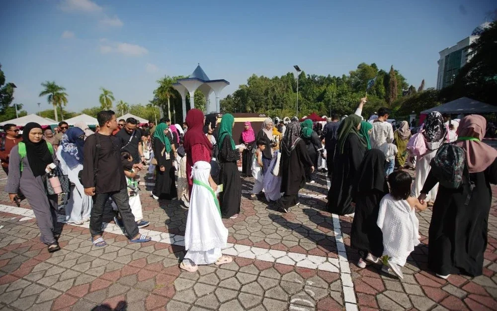 Ibu bapa dan anak-anak sedang melalukan simulasi tawaf sebagai salah satu rukun Haji.