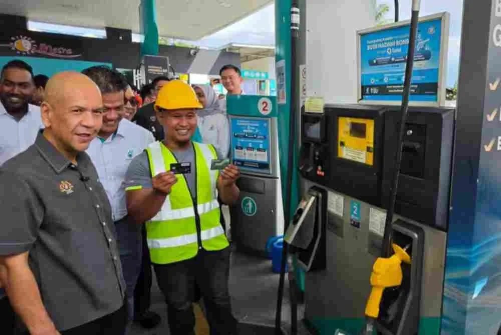 Armizan (kiri) melihat pemandu lori menggunakan kad Fleet di salah sebuah stesen minyak di Kapayan, Kota Kinabalu.