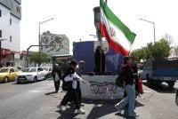 Seorang wanita memegang bendera Iran ketika berada di sebuah jalan di Teheran, Iran pada 10 Jun 2026. Foto WANA (West Asia News Agency).