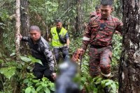 Mayat mangsa dibawa keluar selepas ditemui di kawasan hutan Kampung Togudon, Penampang.