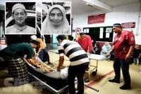 Anak-anak menguruskan jenazah Mohamad Shaufi dan isteri, Kamarsah
di Unit Forensik Hospital Tengku Anis, Pasir Puteh
pada Isnin. HAZELEN LIANA KAMARUDIN