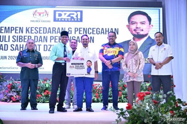 Manndzri (tiga dari kiri) menyampaikan Kad Sahabat DZR1 kepada seorang pelajar sempena Program Kempen Kesedaran dan Pencegahan Buli Siber yang diadakan di Dewan Kejora Bandar Tenggara, di sini pada Isnin.