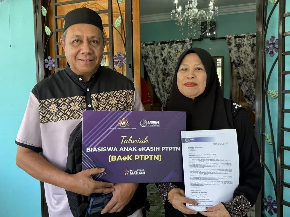 Abu Samah dan isteri, Nor Rizah mewakili anak, Alia Batrisyia menerima kunjungan timbalan menteri dan PTPTN bagi penyerahan BAeK PTPTN di rumahnya di Melaka.