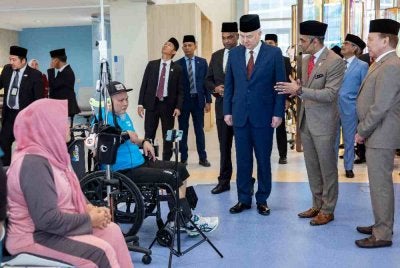 Sultan Nazrin berkenan menyantuni salah seorang pesakit ketika baginda melawat bilik rawatan selepas merasmikan Pusat Rehabilitasi Neuro-Robotik dan Cybernics Pertubuhan Keselamatan Sosial (PERKESO) di Meru Raya pada Selasa. Foto Bernama