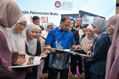 Zambry (tengah) melihat Buku Nahas Gerik: UPSI Berduka bersama sebahagian mangsa yang terselamat dalam tragedi kemalangan bas pelajar UPSI di Gerik pada 9 Jun tahun lepas, pada pelancaran buku itu di Bilik Diraja Dewan Tuanku Canselor UPSI. Foto: Bernama
