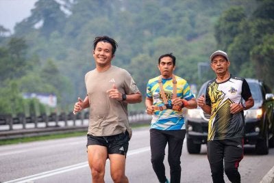 Choo Seong (kiri) turut merakamkan penghargaan kepada sukarelawan dan pelari yang menyertainya sepanjang laluan. - FOTO: Neow Choo Seong