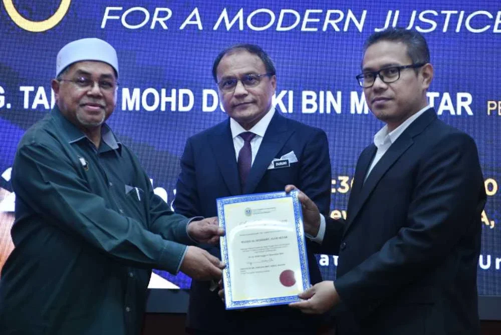 Pengerusi merangkap Imam Masjid Al-Bukhary, Alor Setar, Mohamad Nasrudin Ismail (kiri) menerima sijil penghargaan sebagai Rakan Kolaborasi bagi Projek Komuniti Perdana Jaringan Undang-Undang Sosial Transformasi (AIST) daripada Dr. Ram Al Jaffri sambil disaksikan oleh Mohd Dusuki.