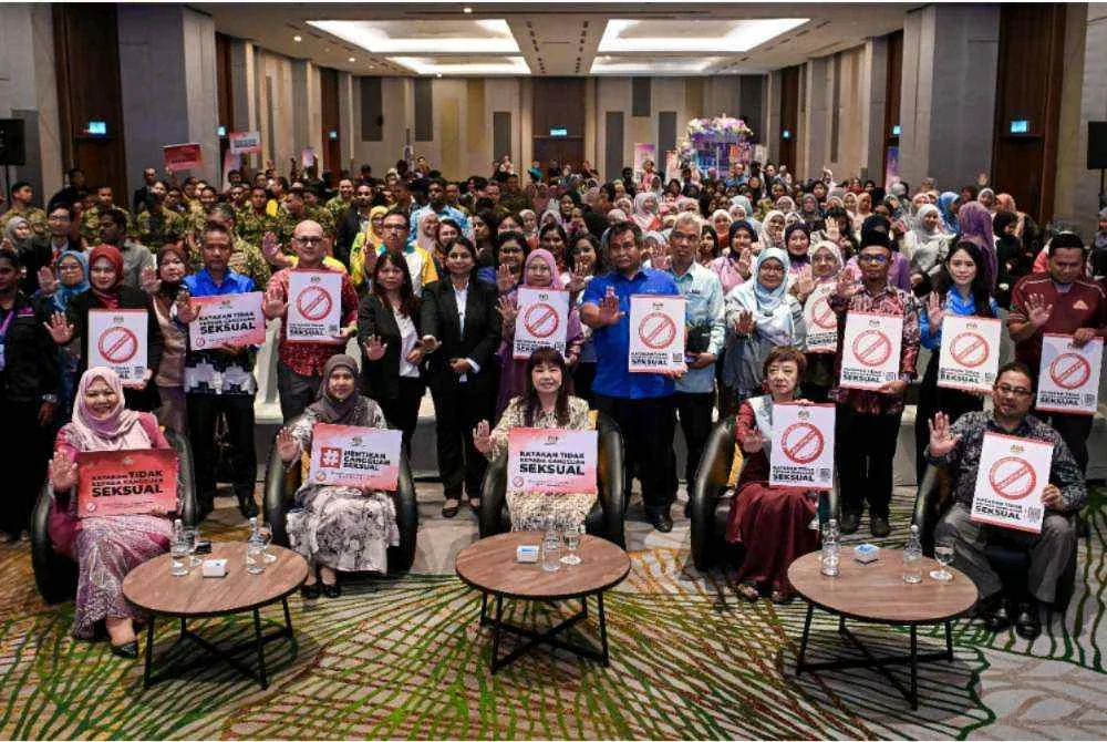 Hui Ying (duduk dari tengah) bergambar bersama orang ramai samnil memegang notis plakad ‘Katakan Tidak Kepada Gangguan Seksual’ pada Program Toleransi Sifar Keganasan: Say No To Sexual Harassment di sebuah hotel. Foto Bernama