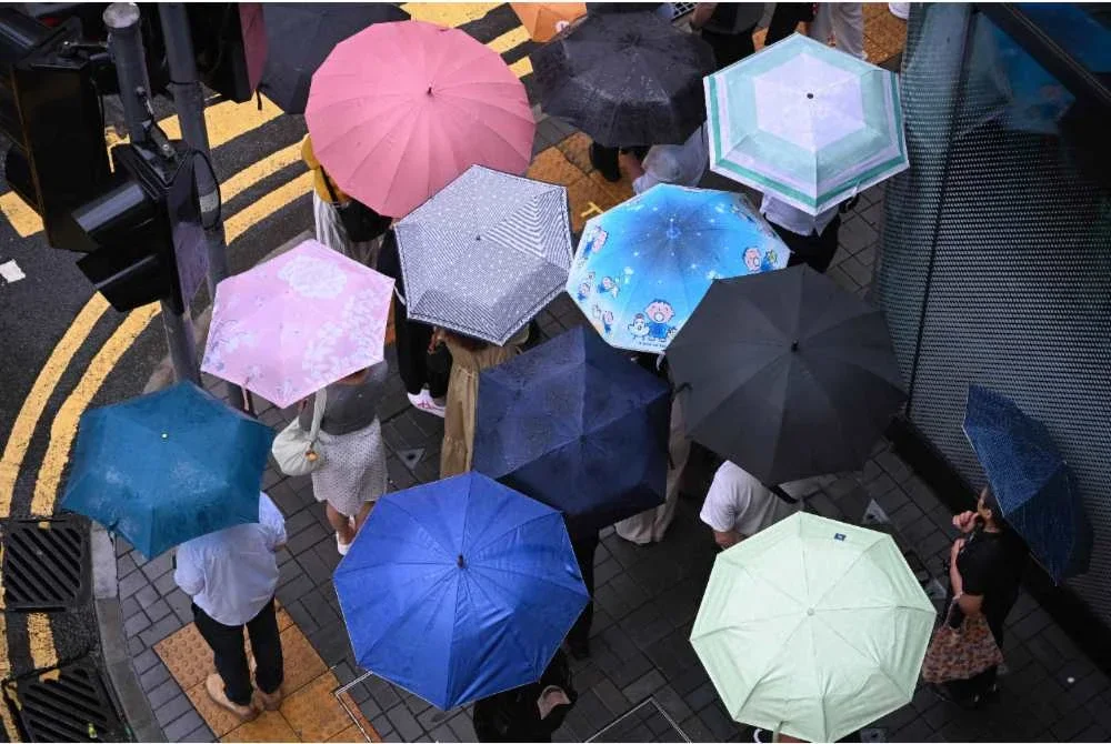 Pejalan kaki dengan payung menunggu untuk melintas jalan ketika hujan lebat di Hong Kong. Foto AFP