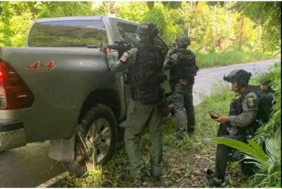 Pegawai polis peronda sempadan bersembunyi di belakang kenderaan peronda berikutan letupan bom di tepi jalan di daerah Than To di Yala pada pagi Jumaat. - Foto: Pejabat Perhubungan Awam Yala