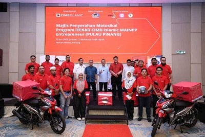 Mohamad (tengah) bersama 20 asnaf yang menerima motosikal dan kelengkapan penghantaran menerusi Program iTEKAD CIMB Islamic-MAINPP Entrepreneur.