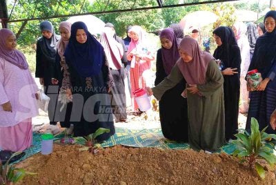 Nurul Alhana Othman, 48, menyiram pusara dua anak kesayangannya.
