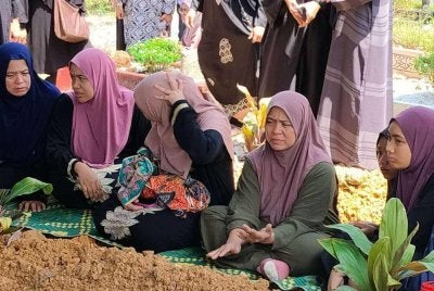 Nurul Alhana (dua dari kiri) sedih namun tetap tenang mengikuti proses pengebumian jenazah dua anak perempuannya.