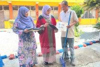 Nur Aina Najwa (tengah) menunjukkan keputusan cemerlang yang diperolehi kepada bapanya (kanan) yang juga tukang kebun sekolah.