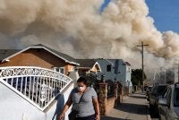Seorang penduduk memakai pelitup muka ketika kebakaran besar di sebuah gudang kemudahan storan sejuk terus marak dan menyebarkan asap di sekitar bandar di Los Angeles, California. Foto AFP