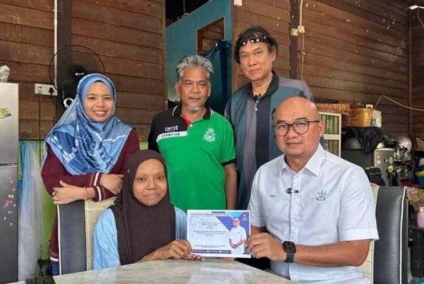 Fadzli (kanan) menyampaikan sumbangan kerajaan Pahang berjumlah RM10,000 bagi membantu menampung kos rawatan yang diperlukan Syazwani. Foto Facebook Fadzli