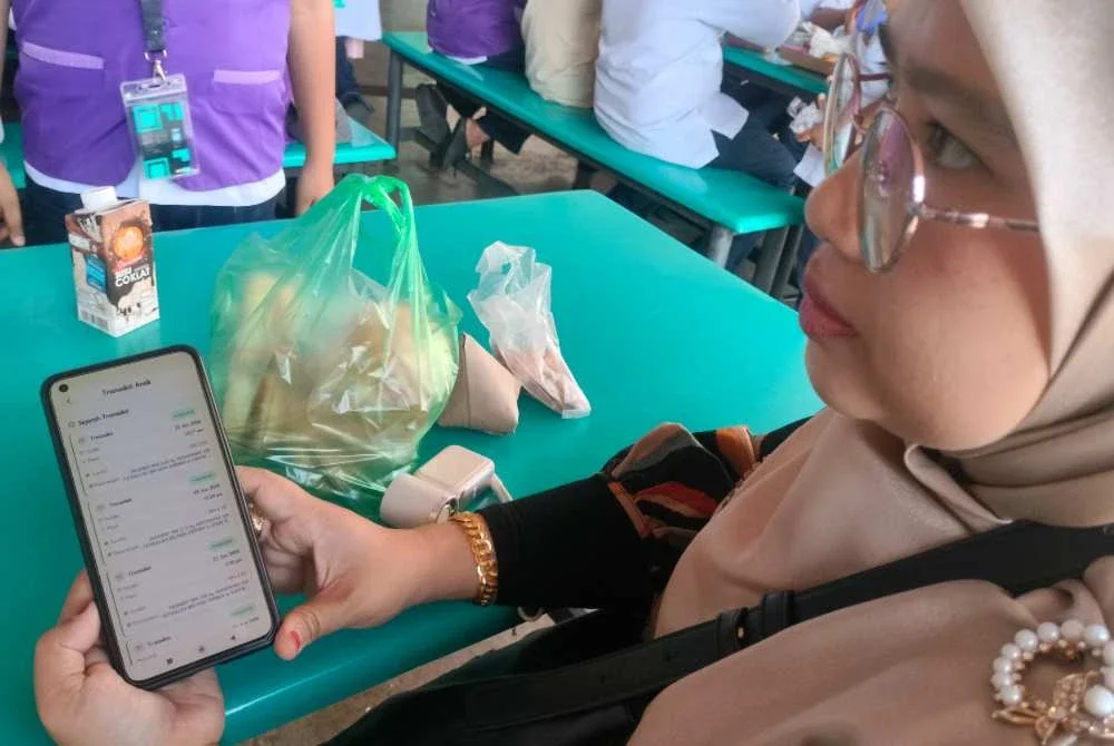 Raniza menunjukkan aplikasi yang digunakan untuk memantau pembelian di kantin dan koperasi.