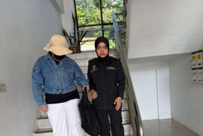 Tertuduh diiringi pegawai UPNP ketika dibawa ke Mahkamah Sesyen Raub pada Isnin bagi menghadapi tuduhan menduduki tanah kerajaan negeri secara haram kira-kira dua tahun lalu.
