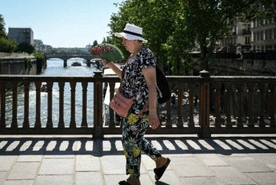 Seorang wanita menggunakan kipas tangan untuk menyejukkan tubuhnya setelah suhu luar biasa melanda tengah Paris. Foto AFP