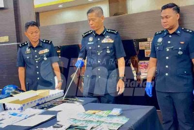 Dennis Lim (tengah) menunjukkan wang tunai yang dirampas dalam 12 tangkapan menerusi Op Soga XI.