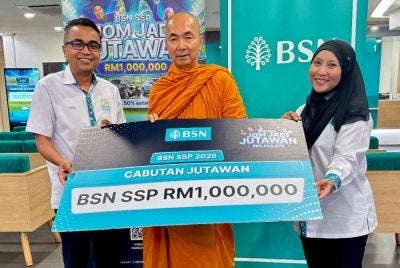 Mohd Hairul (kiri) dan Aizurra menyampaikan replika cek kepada Chai Siang di Cawangan Utama BSN Pulau Pinang di Jalan Macalister pada Selasa.