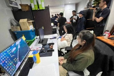 Pegawai menyerbu sebuah rumah di Nonthaburi, Thailand, yang dipercayai menjadi lokasi pengubahan jawapan peperiksaan calon jawatan kerajaan tempatan. Foto Bangkok Post.