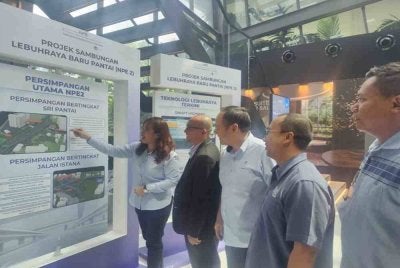 Lay Hoon (kiri) melihat lakaran pelan lokasi berkaitan Projek Sambungan NPE 2 di sini pada Rabu.