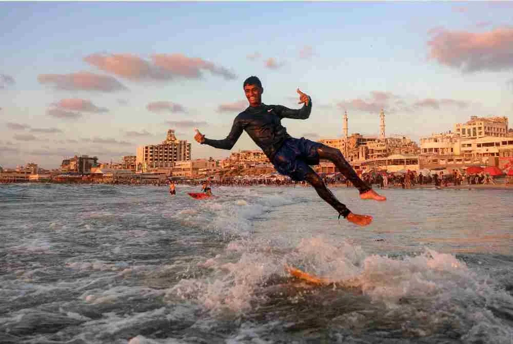 Seorang peluncur melompat daripada papan luncur di pantai Gaza, menikmati seketika kebebasan di tengah ketidaktentuan yang masih menyelubungi wilayah itu. Foto: AFP