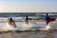 Aksi mereka menuju ke laut dengan papan luncur, memanfaatkan ombak yang tenang di sebalik konflik yang belum benar-benar reda. Foto: AFP