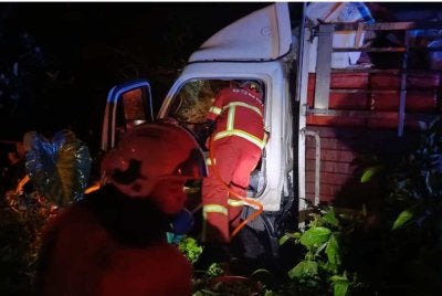 Anggota bomba sedang mengeluarkan pemandu lori yang tersepit.