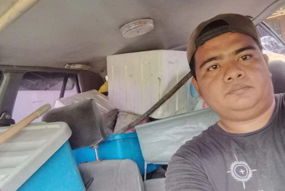 Muhamad Firdaus ketika melakukan kerja-kerja mengutip sampah menggunakan Proton Iswara lama milik ibunya.