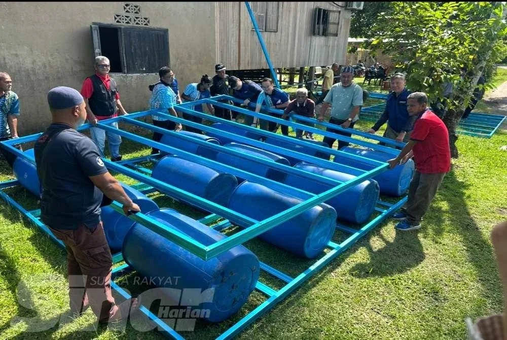 Dr Sao Chin (dua dari kanan) membantu mengangkat zink untuk dibuat bumbung rakit. FOTO: ADILA SHARINNI WAHID