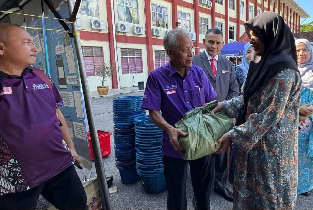Muhammad Nasir (tengah) menyampaikan barangan keperluan kepada mereka yang hadir sempena Sambutan Hari Koperasi Sekolah, Hari Kokurikulum, Hari TVET dan Hari Seni dan Budaya di SMK Pelagat, Jertih, Besut, baru-baru ini.