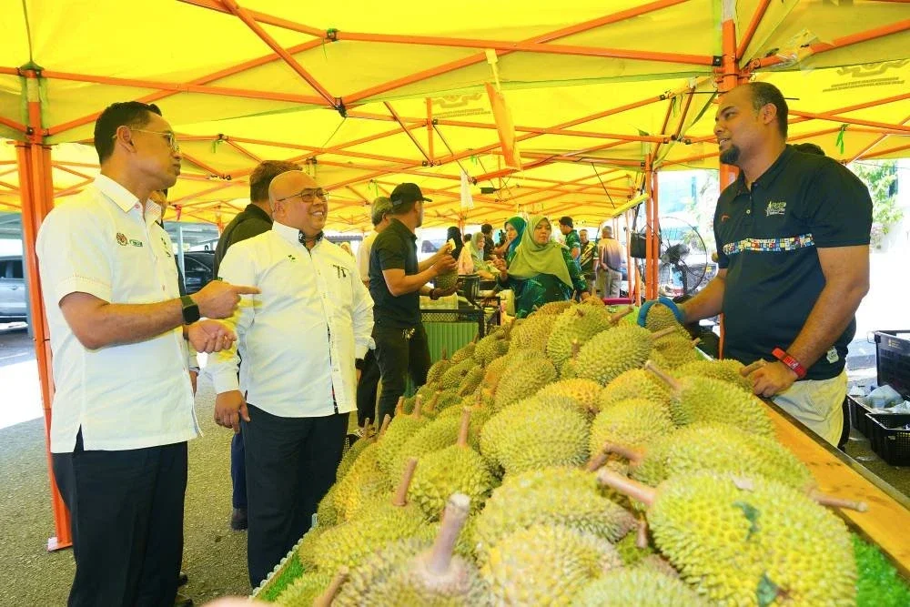 Faisal (dua dari kiri) sedang mendapatkan maklumat mengenai jualan buah durian daripada salah seorang penjual.