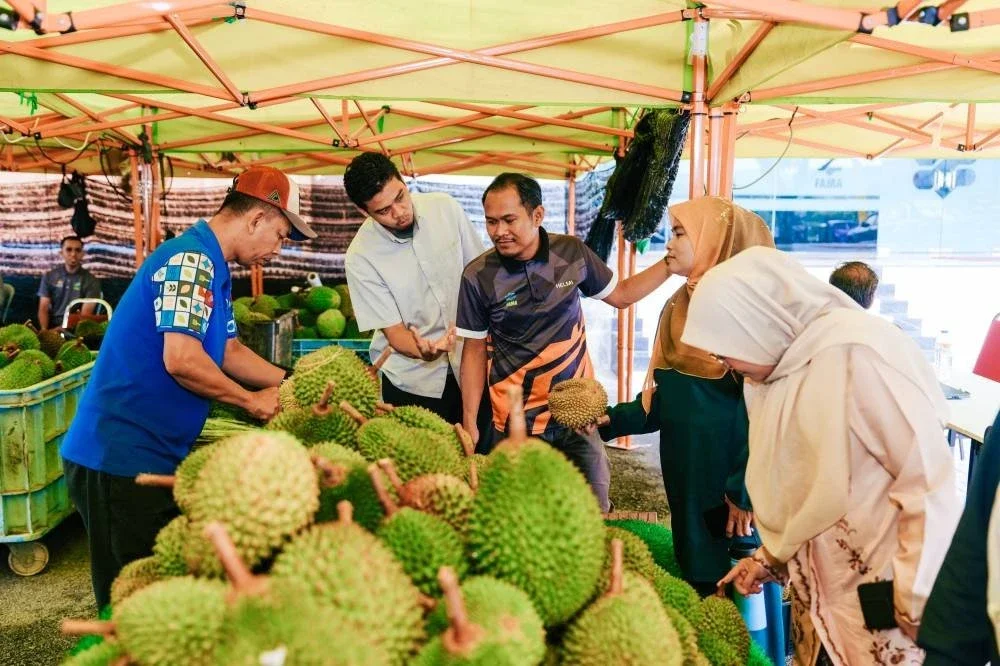 Pengunjung meneliti dan memilih durian sebelum membuat pembelian di gerai jualan.
