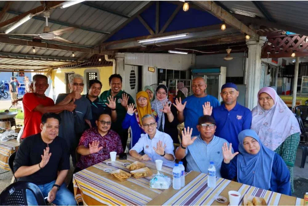 Fahmi bergambar bersama sebahagian penduduk sekitar pada Program Edaran Pisang Goreng Percuma di Medan Selera Banang, Taman Banang Jaya pada Jumaat. Foto Bernama