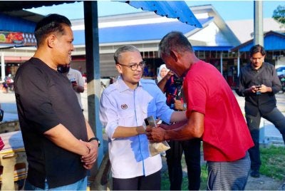Fahmi menyantuni penduduk sekitar pada Program Edaran Pisang Goreng Percuma di Medan Selera Banang, Taman Banang Jaya pada Jumaat. Foto Bernama