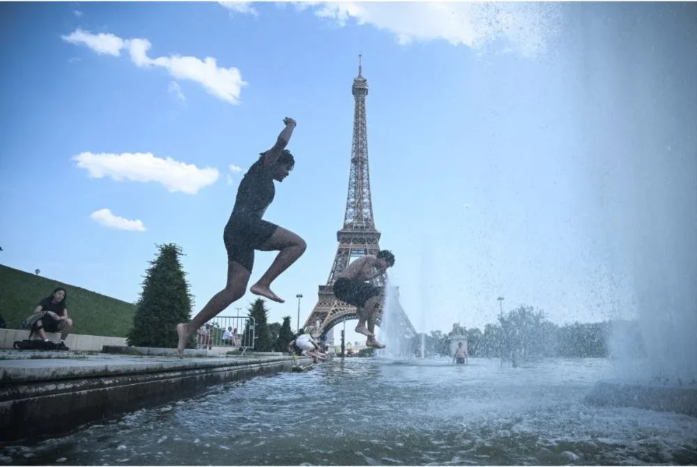 Orang ramai menyejukkan badan dengan mandi di kolam air pancut Trocadéro berhampiran Menara Eiffel.