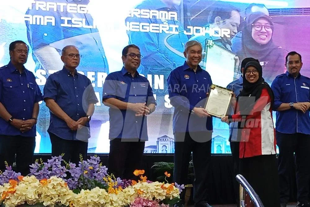 Ahmad Zahid (lima dari kiri) menyampaikan penghargaan kepada kakitangan Kemas di MRSM Tun Dr Ismail, Pontian pada Sabtu.