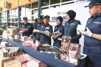 Hasbollah (empat, kanan) menunjukkan antara rokok seludup yang dirampas dalamempat siri serbuan berasingan di sekitar Terengganu dan Kelantan sepanjang April hingga Mei lalu. 