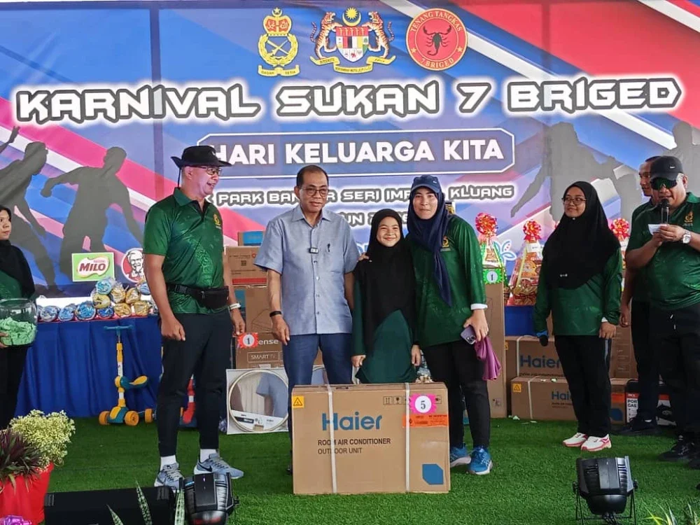 Mohamed Khaled (dua dari kiri) menyerahkan hadiah kepada pemenang cabutan bertuah sempena Karnival Hari Keluarga Kita bersama warga Angkatan Tentera Malaysia (ATM) Zon Selatan di Kluang pada Ahad.